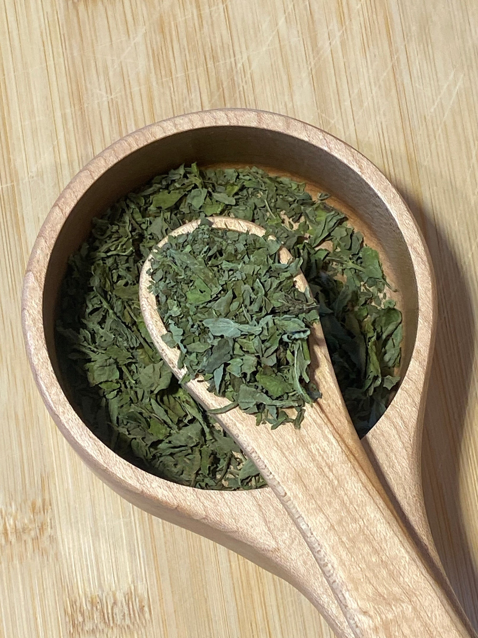 Premium dried basil leaves grown in Texas  shown in a spoon and bowl for culinary flavors and cooking.
